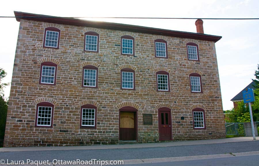 three-storey beige stone mill with arched windows