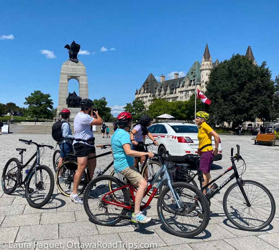 Cyclists gathered at the foot of the National War Memorial (large granite arch) in Confederation Square in Ottawa.