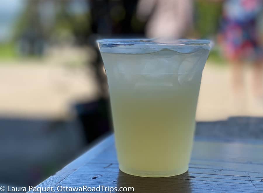 lemonade in a plastic glass on a wooden table against a blurred background