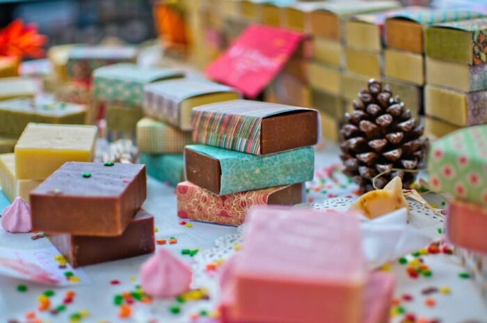 handmade soaps wrapped in festive paper on a table with pinecones