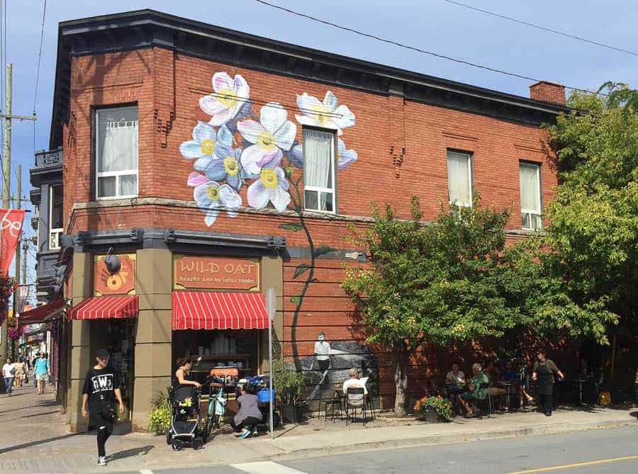 red brick two-storey building in the glebe with flower mural, and tables and chairs on sidewalk
