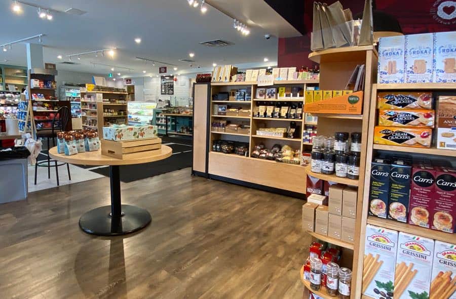 large shop with wood floors and shelves, with displays of crackers, jams and other packaged goods.