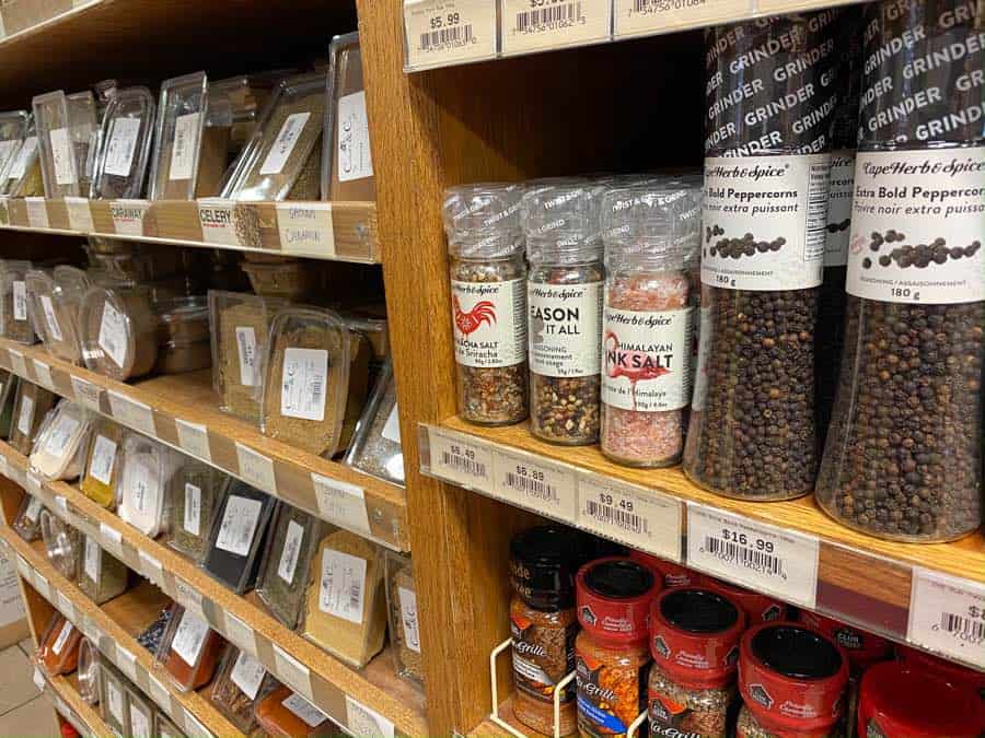 Closeup of shelves of salt, pepper and spices in jars and plastic tubs.