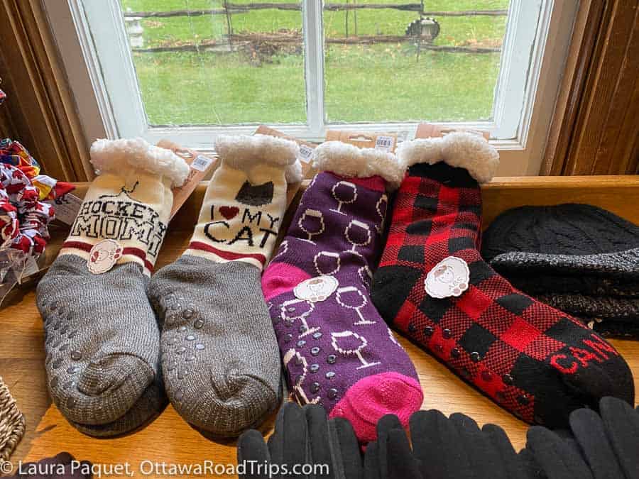 thick, colourful christmas socks on a wooden table, with a window looking out onto a green lawn behind.