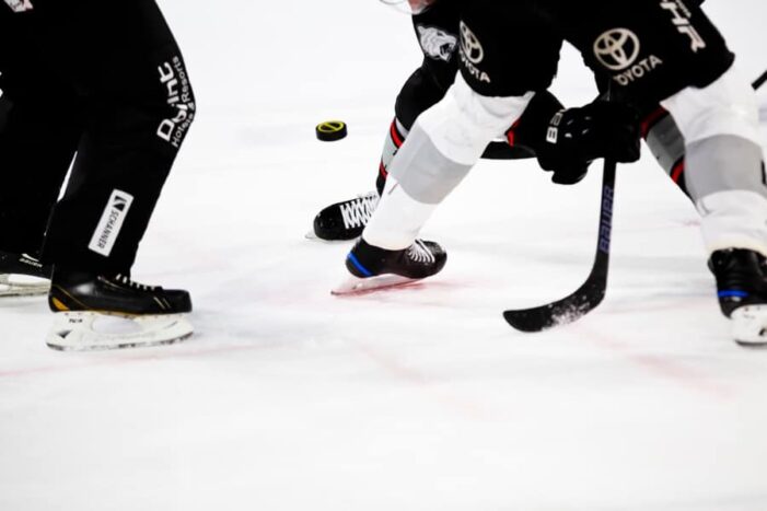 markus-spiske-hockey-unsplash - Ottawa Road Trips closeup of three hockey players' feet in skates, with a stick and puck