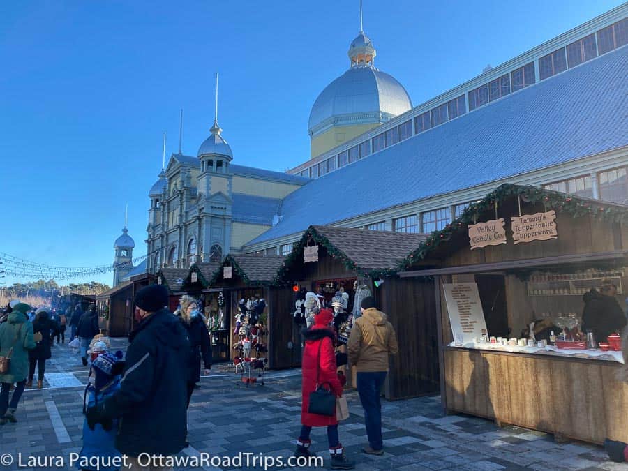 wooden vendor huts in front of aberdeen pavilion (large yellow domed building) at an ottawa christmas market
