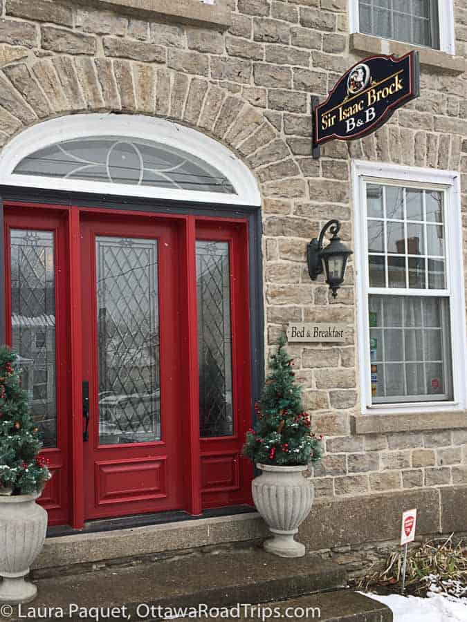 stone mansion with a bright red door, carriage lamp and mullioned windows.