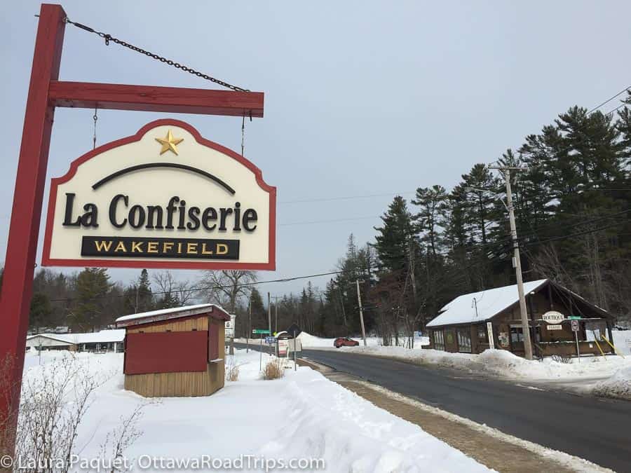 la confiserie wakefield hanging sign beside a snowy road