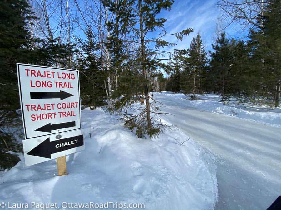red and white signs beside forest skating trail in lac-des-loups, quebec