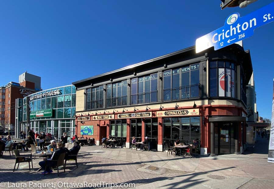 royal oak pub in brick and glass building in new edinburgh with people eating on sidewalk patio