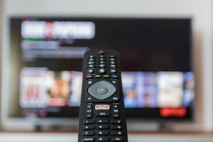 TV remote in foreground with blurred television in background.