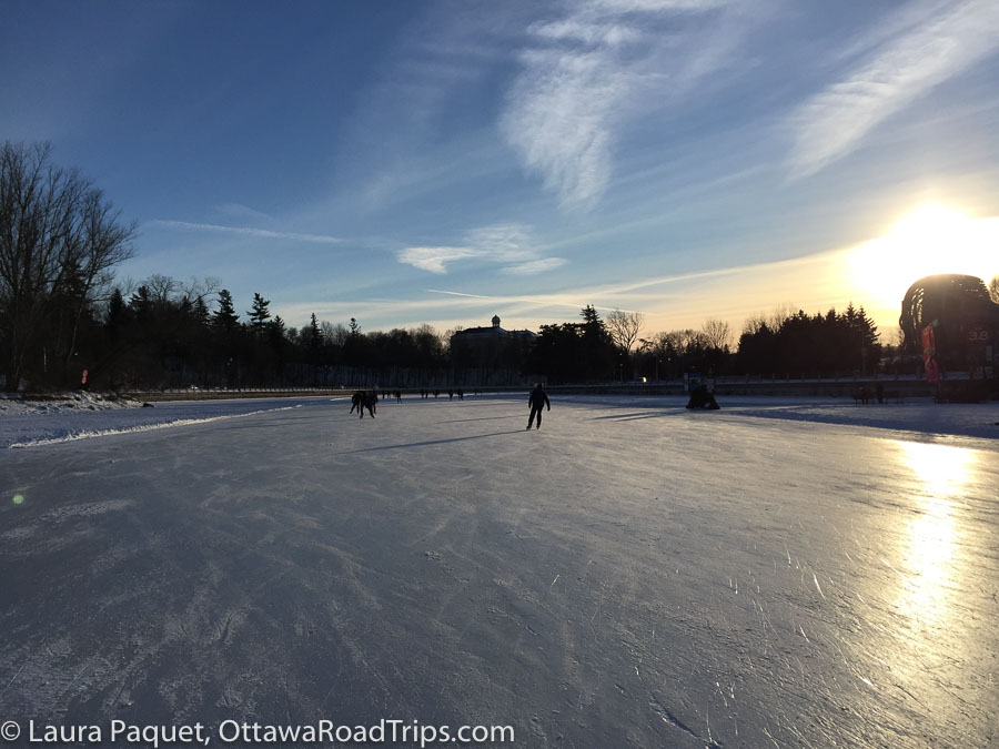 Rideau Canal Skateway with a few skaters silhouetted against the sun.