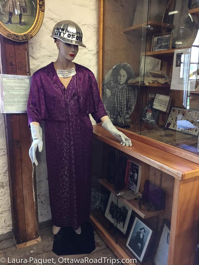 mannequin in purple dress in front of display of Charlotte Whitton memorabilia at McDougall Mill Museum in Renfrew
