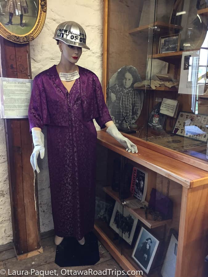 mannequin in purple dress in front of display of charlotte whitton memorabilia at mcdougall mill museum in renfrew