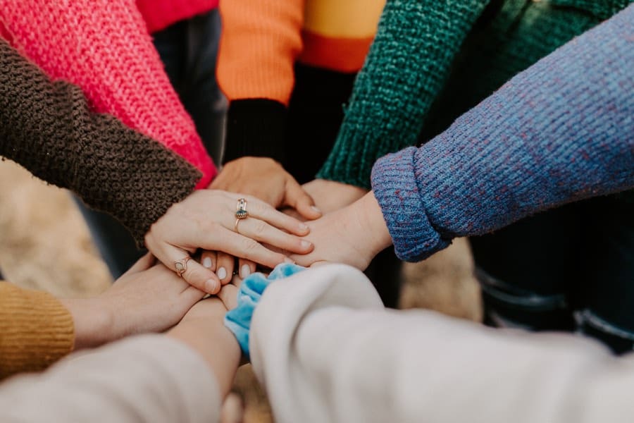 Many hands on top of each other in the middle of a circle.