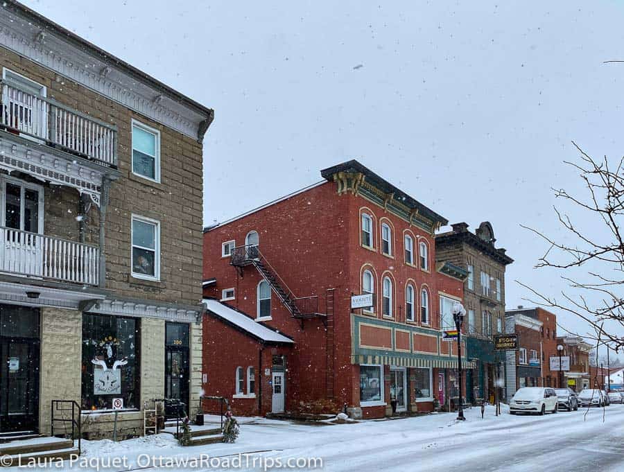 grey stone and red brick buildings from 19th and early 20th centuries, with arched windows and interesting roof details, along prescott street in kemptville
