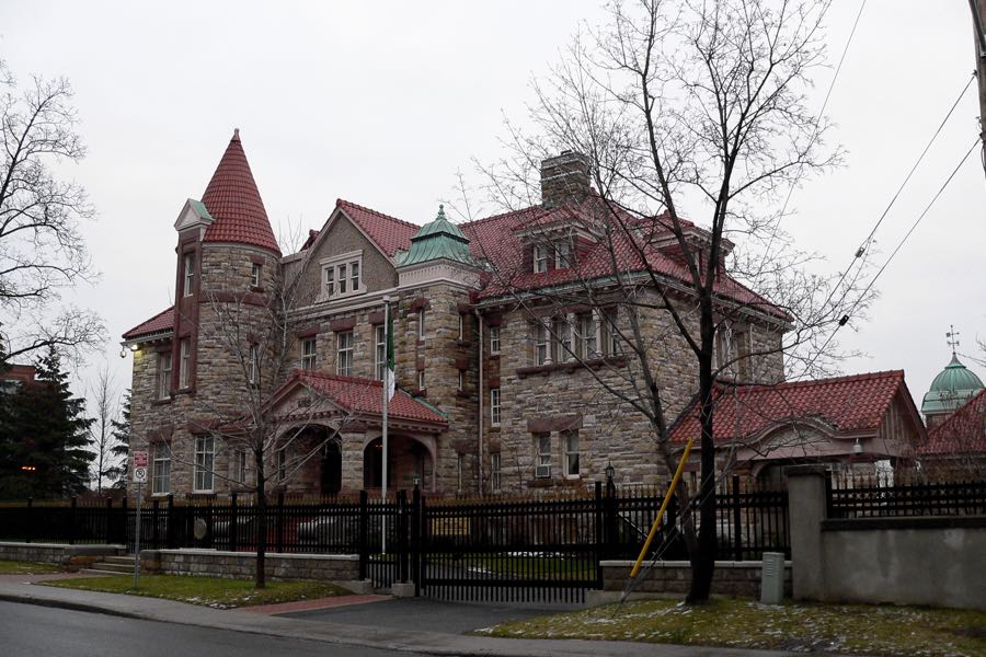 the fleck-paterson house in ottawa is a large grey stone house with red tiled roofs, a porte-cochere and a turret.