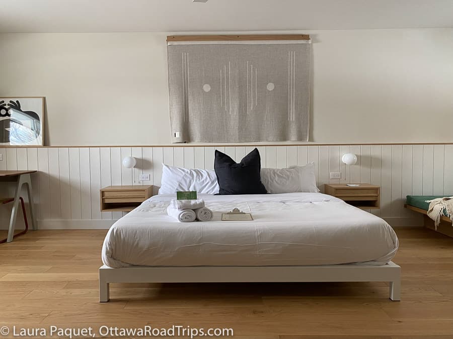 platform bed with white linen on light wood floor with earth-toned decor at the somewhere inn in calabogie, ontario.