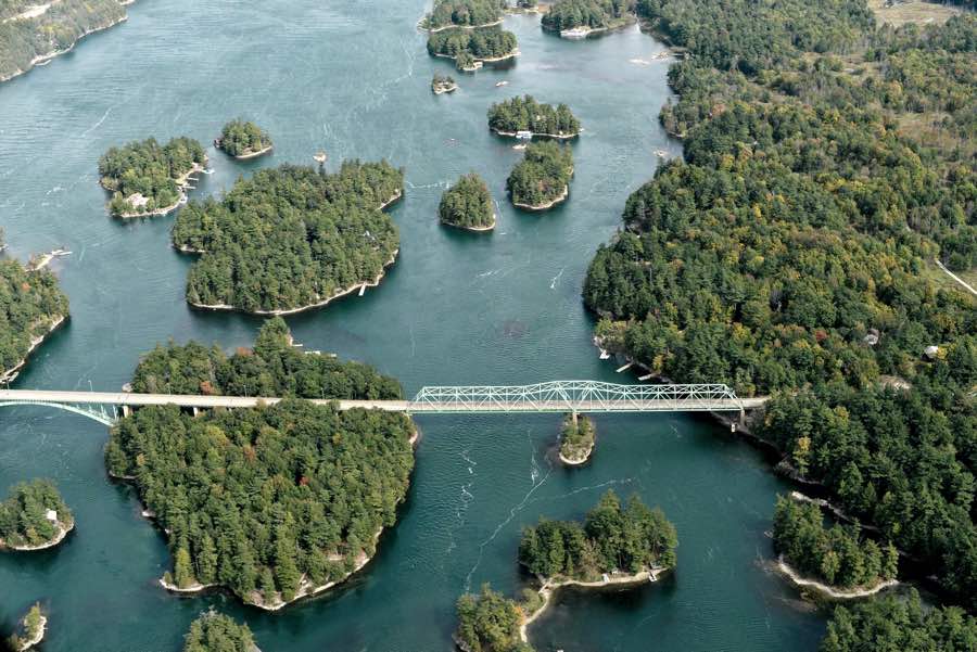 aerial view of many of the 1000 islands near kingston, with white bridge crossing several of them.