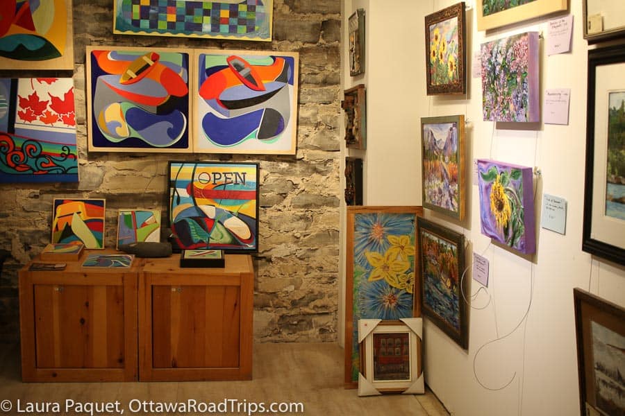 abstract paintings hanging on stone wall and landscape paintings hanging on adjacent plaster wall
