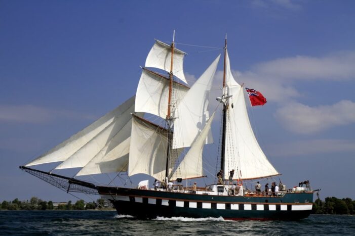 tall ship with white sails against a blue sky