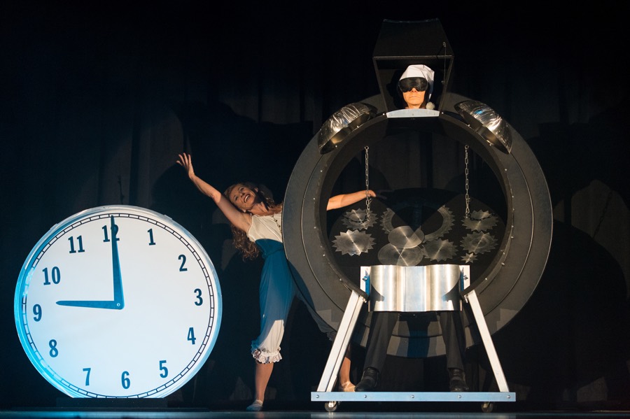 woman in a Victorian-style camisole and bloomers next to masked man apparently cut in two by a giant clock