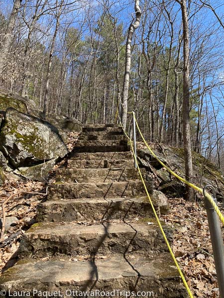 stone stairs carved into rocky hillside with a yellow rope on right, on trail 1 at parc régional de mont-morissette. 