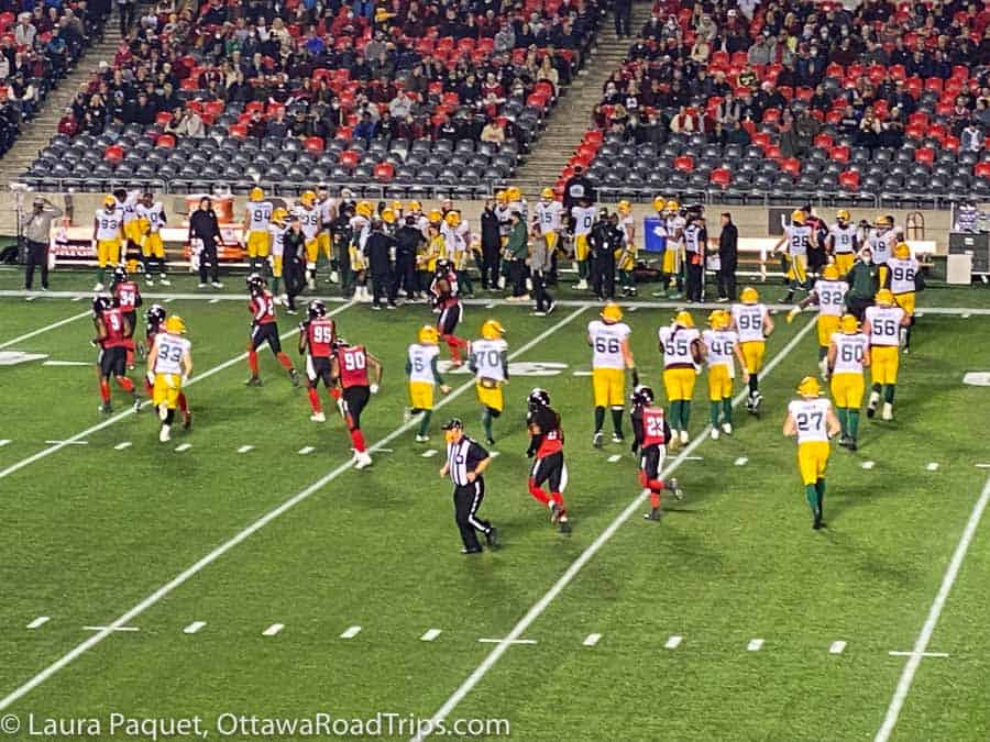 Ottawa Redblacks and Edmonton players playing on green field with stands in background