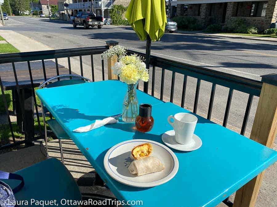 scrambled egg wrap on a blue table with a vase of flowers and village street in background