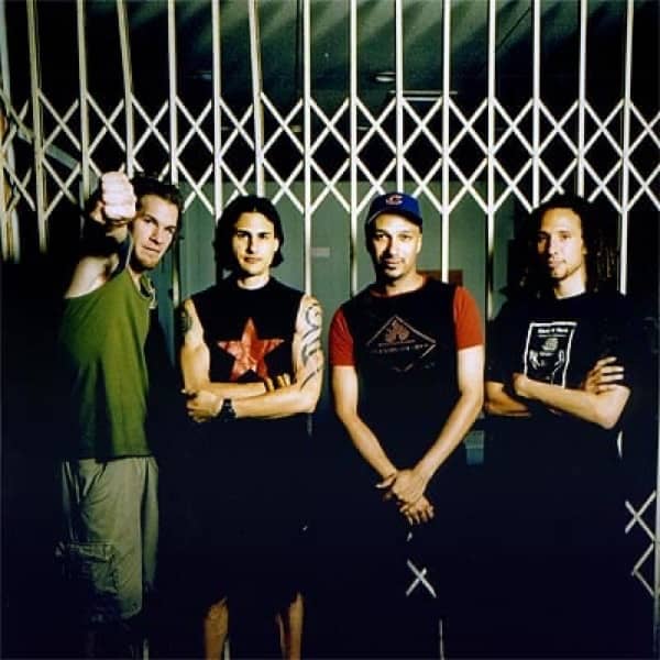 four men in t-shirts against a green-and-white wall