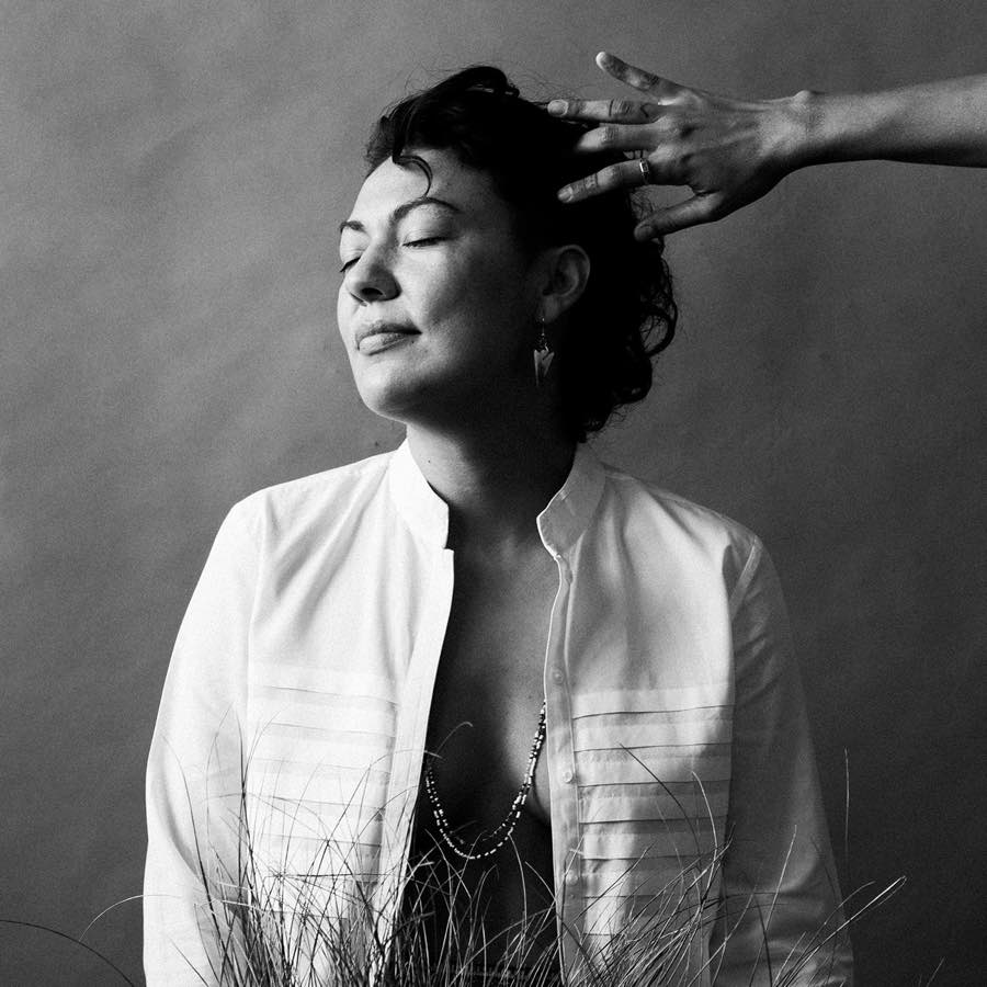 Black and white photo of an Indigenous woman with a hand touching her hair