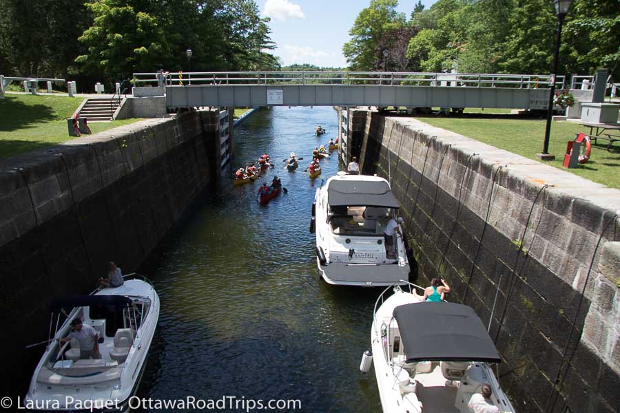 motorboats and kayaks, photographed from above, passing through the open gates of chaffeys lock in elgin (rideau lakes).