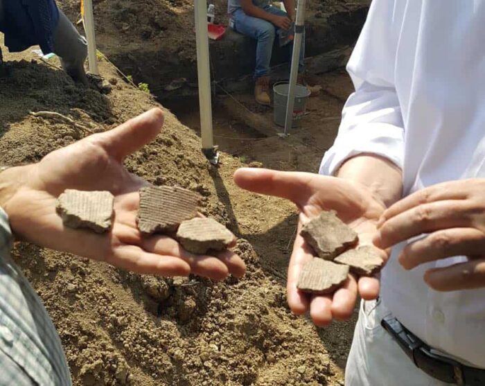 closeup of hands holding archaeological fragments