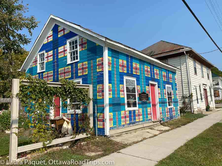 wooden house painted in a blue, yellow and red plaid in lyndhurst, ontario.