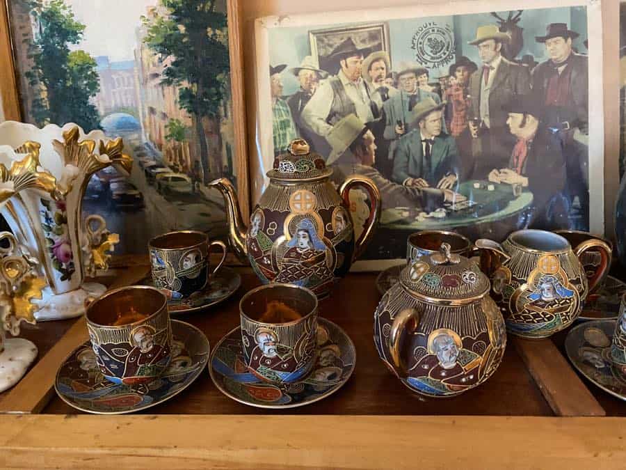 lacquered chinese tea set in foreground with print of cowboys around a poker table in background.