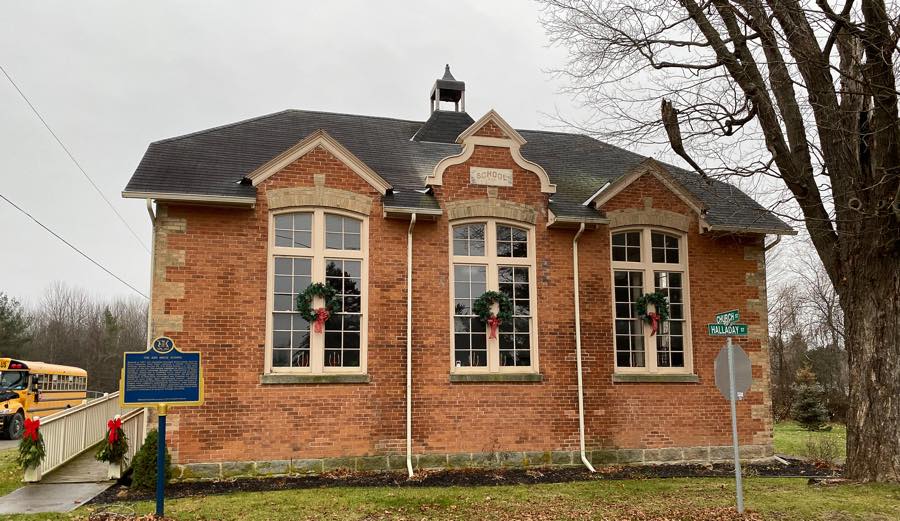 exterior of victorian red-brick schoolhouse with large mullioned windows and a fancy middle gable in the rideau lakes community of elgin, ontario.