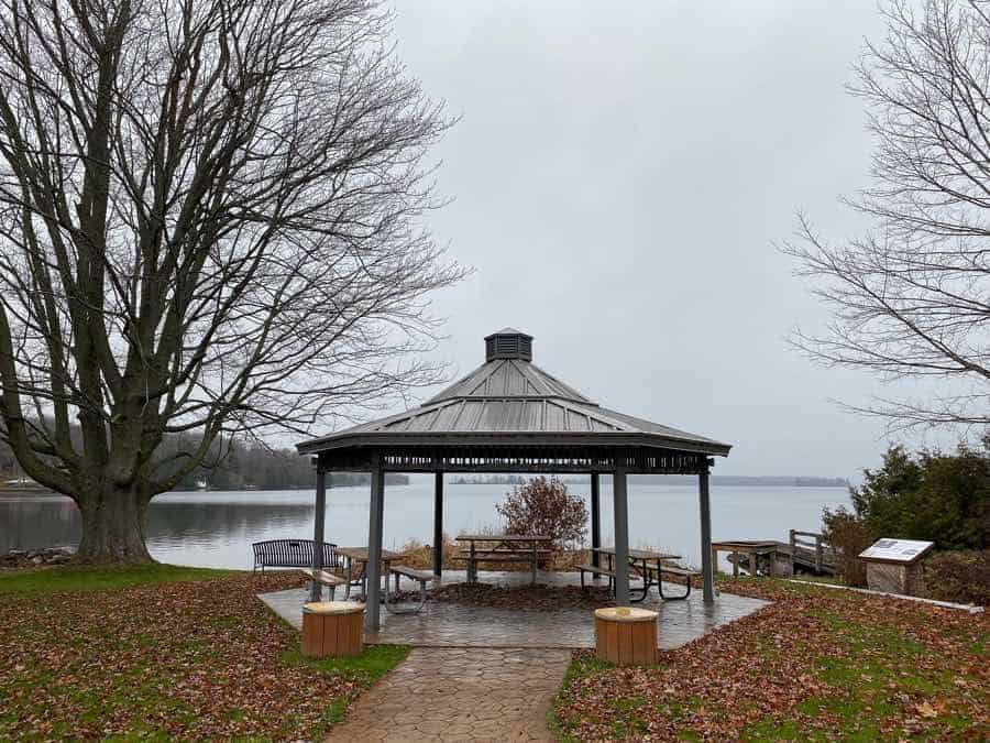 gazebo-style picnic shelter overlooking a small lake in fall at hanna park in portland, ontario.