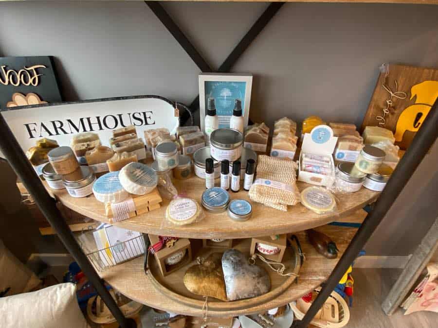 Semi-circular wooden shelf displaying soaps, loofahs and other gifts.