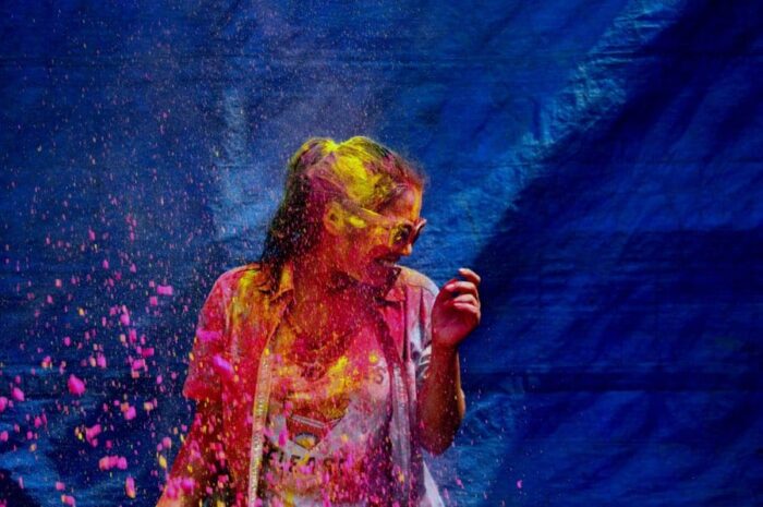 varun-verma-holi-unsplash - Ottawa Road Trips woman covered with pink and yellow paint against a blue backdrop