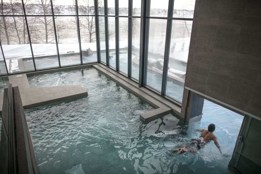 indoor pool with glass windows overlooking st. lawrence river and passage to outdoor pool at strom spa quebec city.