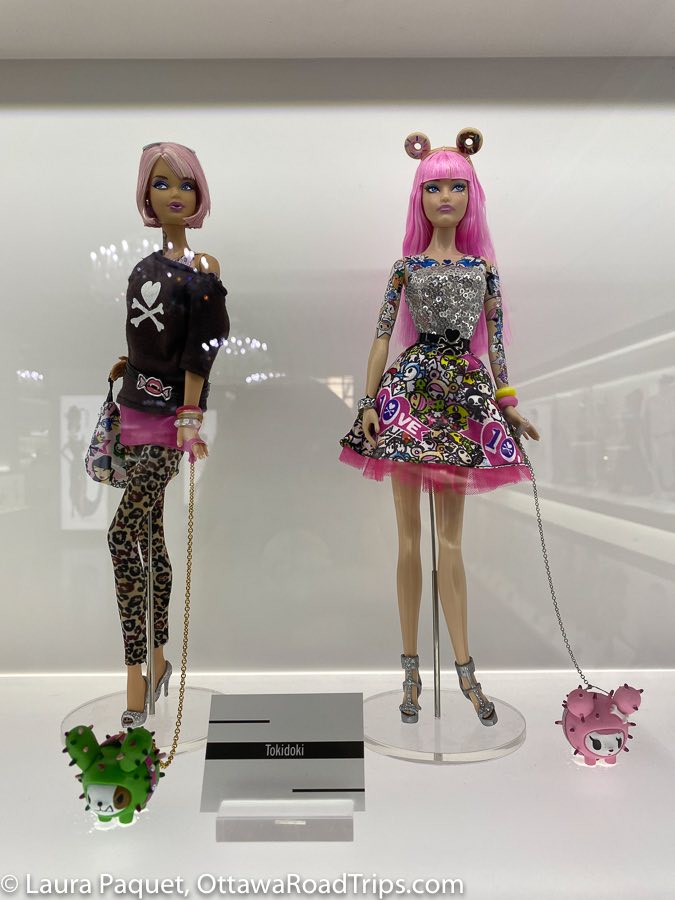 barbies with pink hair, one wearing leopard-print leggings and the other in a mini dress with silver top and cartoon-patterned skirt