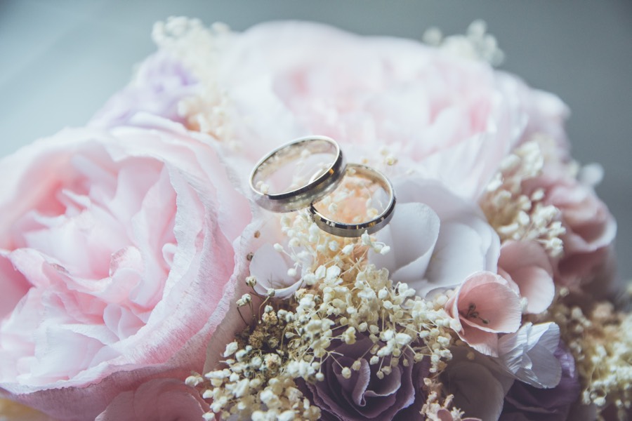 closeup of pink roses and white baby's breath flowers with two wedding rings on top