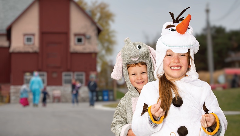 children dressed as elephant and as olaf from frozen in front of old barn.