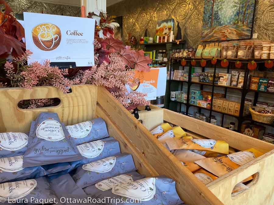 Wooden boxes filled with packages of caramels, with black shelves of packaged foods in background.