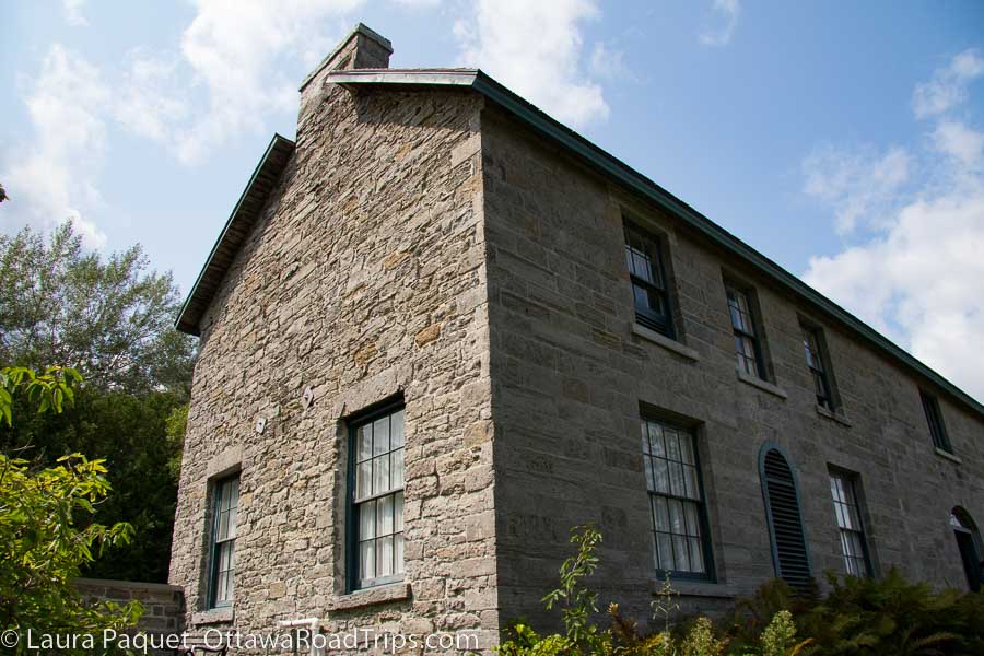 Pinhey's Point in Ottawa is a large two-storey limestone mansion with mullioned windows and arched door.