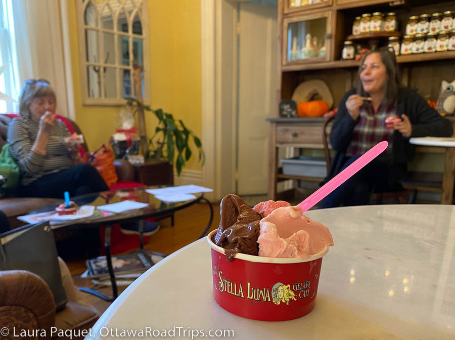 Red cup filled with three small scoops of gelato on a white marble table.