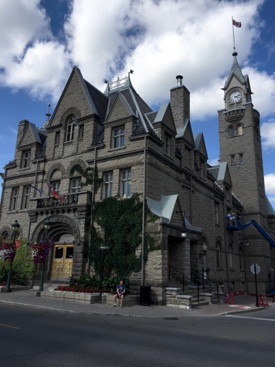 The Carleton Place Town Hall is a large three-storey limestone building with an arched doorway and a clock tower.