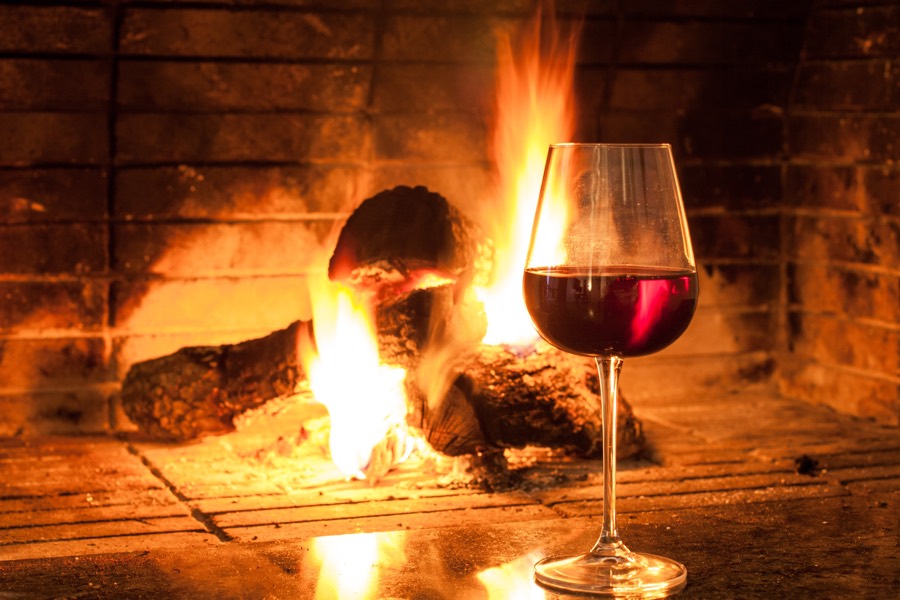 glass of red wine in front of a roaring fire