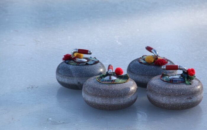 four curling rocks with tartan ribbons on ice