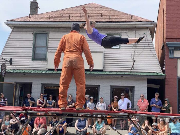 kemptville-buskerfest-trampoline - Ottawa Road Trips woman jumping on a trampoline in front of a shop, surrounded by spectators